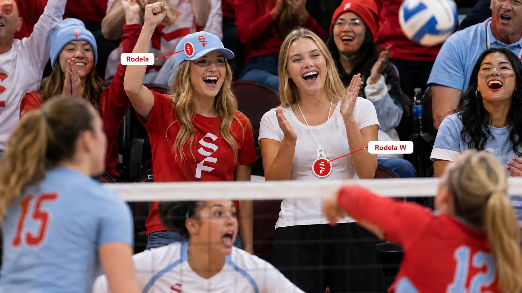 Fans cheering in the stands at a volleyball match, one wearing a snap-on Rodela badge on her cap and another wearing a Rodela W badge on a lanyard, with callout labels naming Rodela and Rodela W.